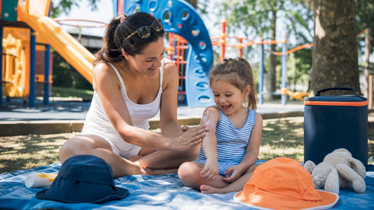 Parent applying sunscreen to child in park