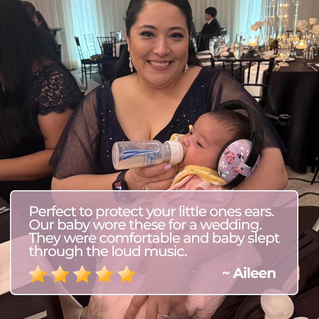 Woman holding a baby with ear protection, sitting at a formal event.